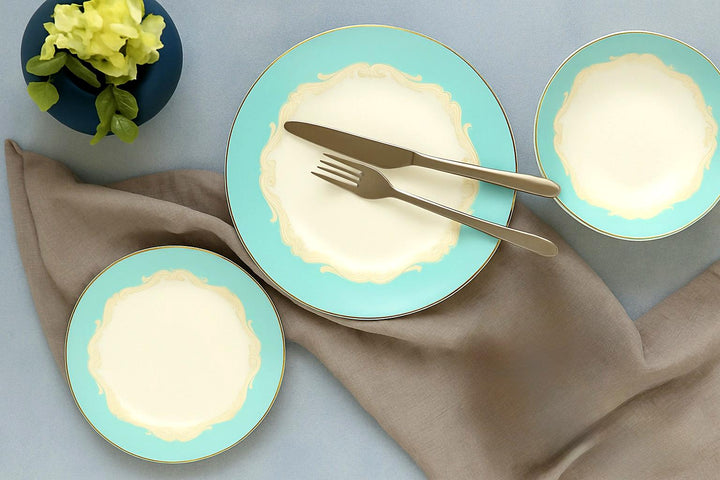 Flatlay of Alba Royal Bone China Dinner Set – turquoise and cream plates with gold detailing, styled with cutlery, linen napkin, and flower vase